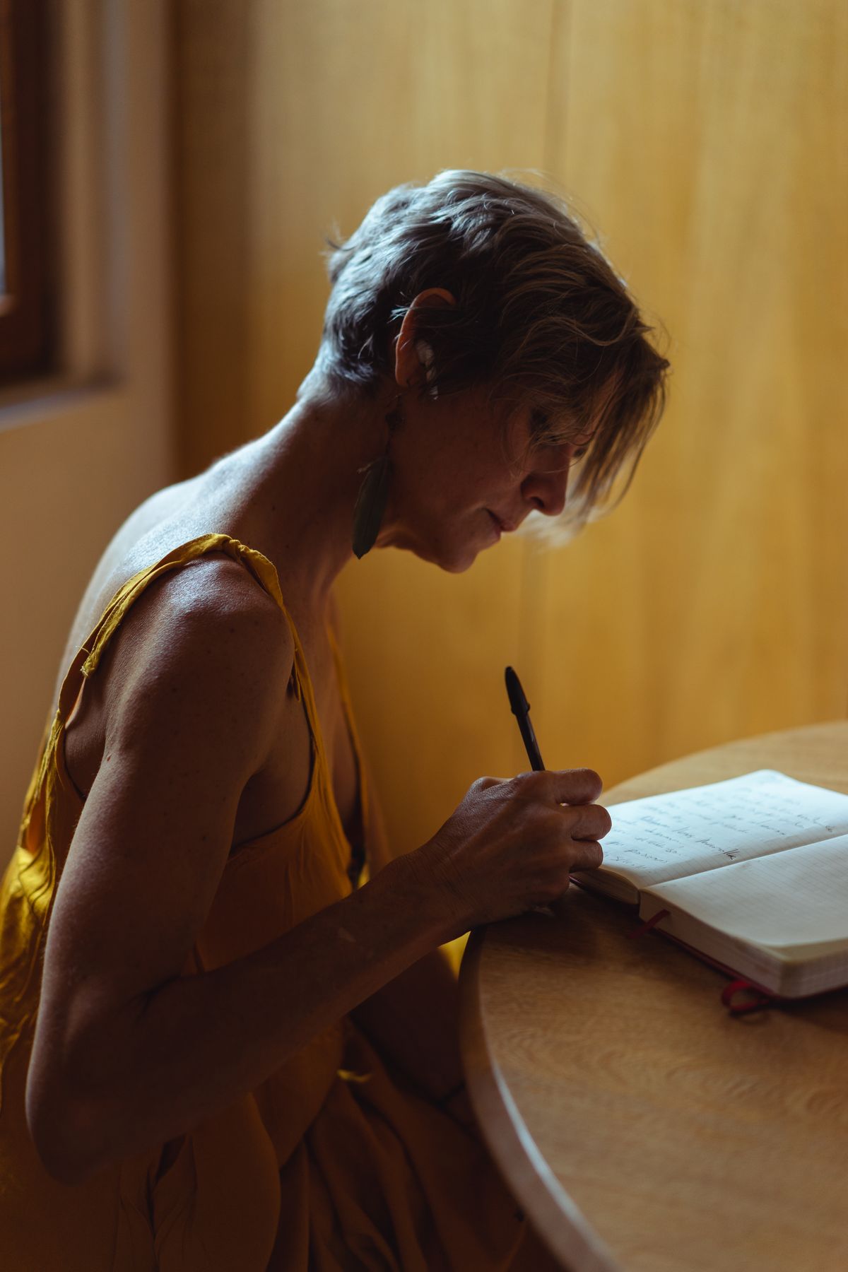 A person writing in a notebook by a sunlit window